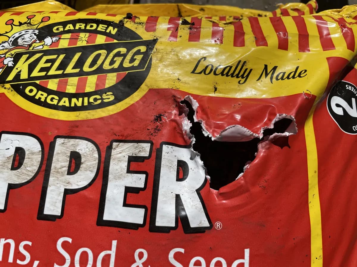 Bag of garden soil with a hole punched through the front