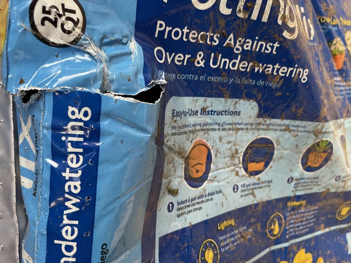 Bag of potting mix with a torn corner spilling soil